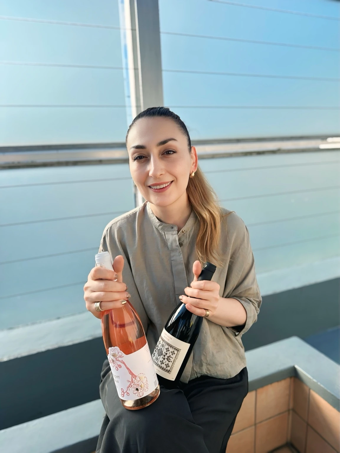 Thea Matins holding two wines with labels she designed
