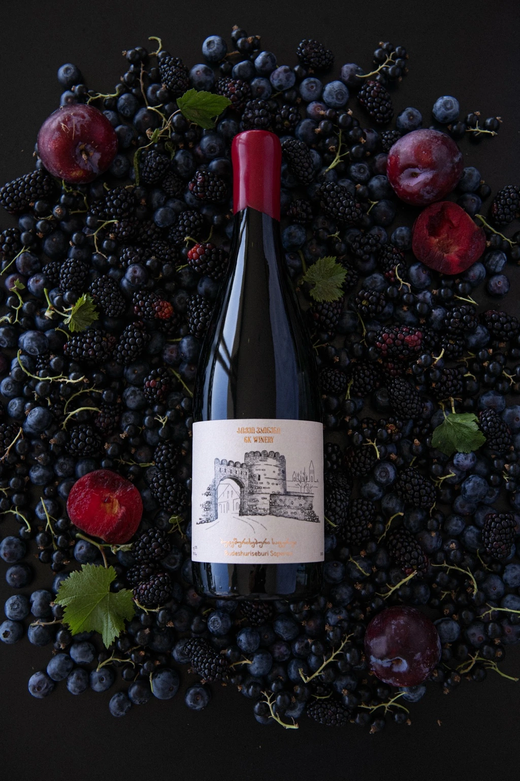 GK Winery bottle arranged with dark grapes and pomegranates