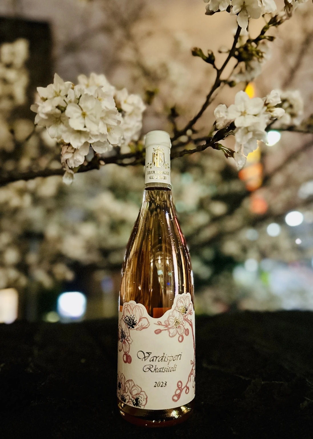 Vardisperi Rkatsiteli bottle photographed beneath cherry blossoms